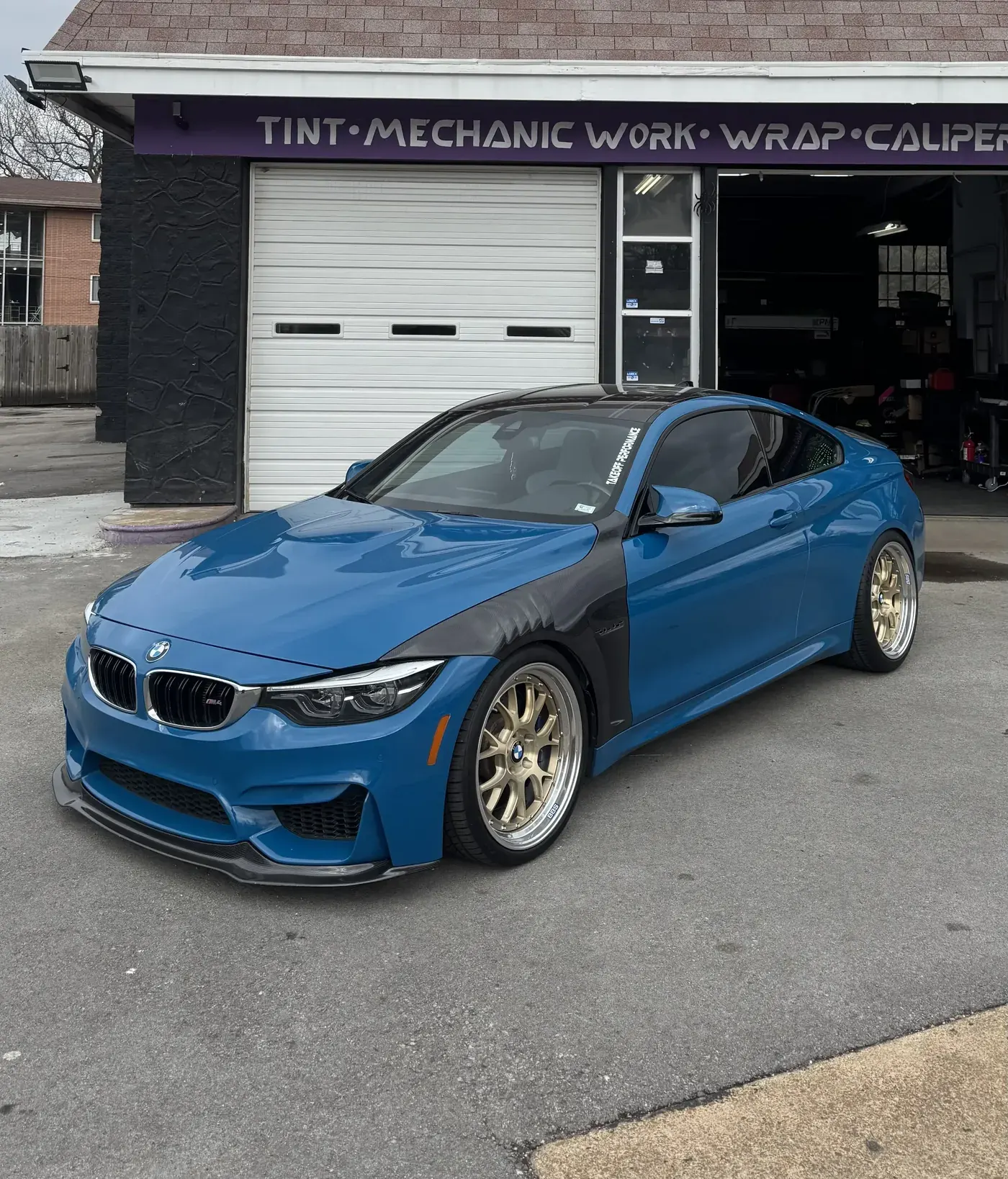 Blue BMW M4 with paint protection film in front of the shop