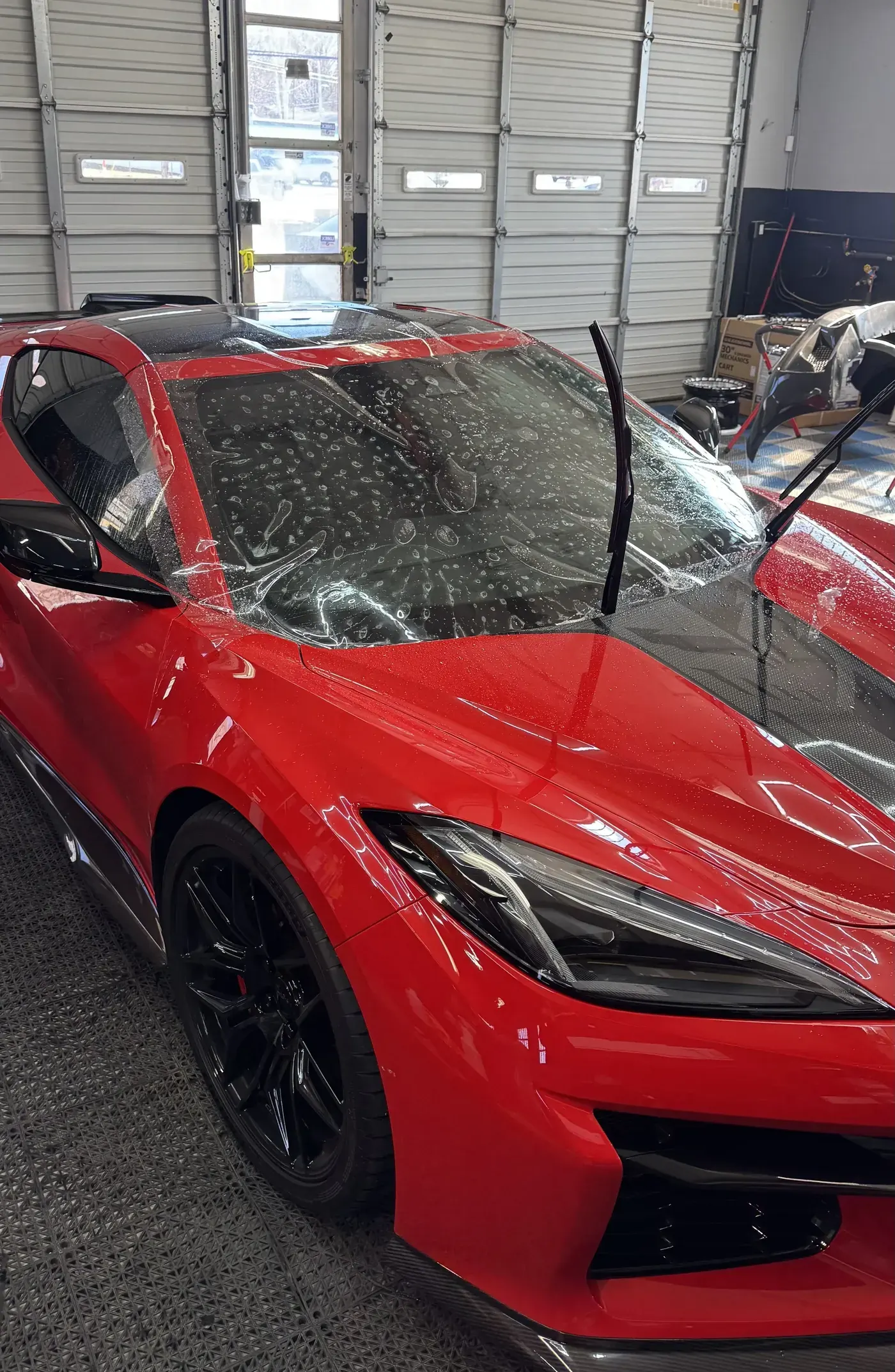Red Corvette getting paint protection film in the bay