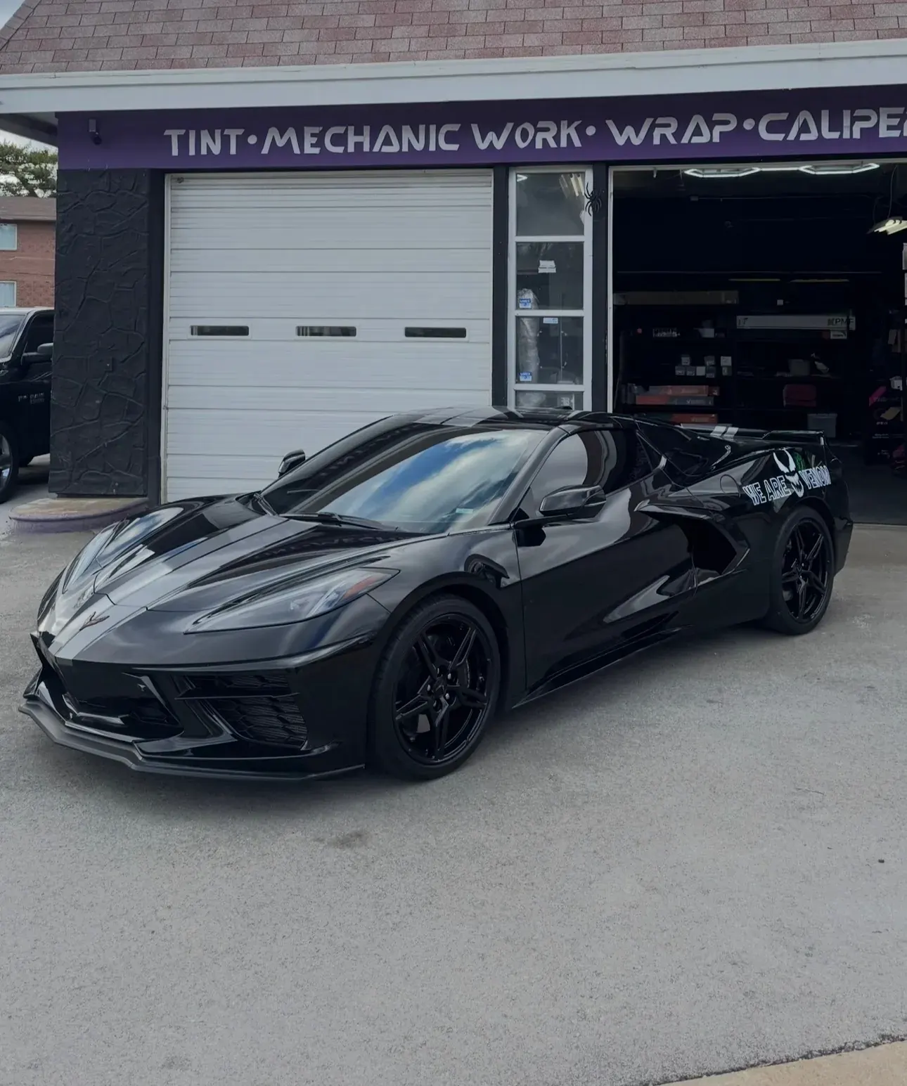 Black Corvette with powder coated wheels in front of the shop