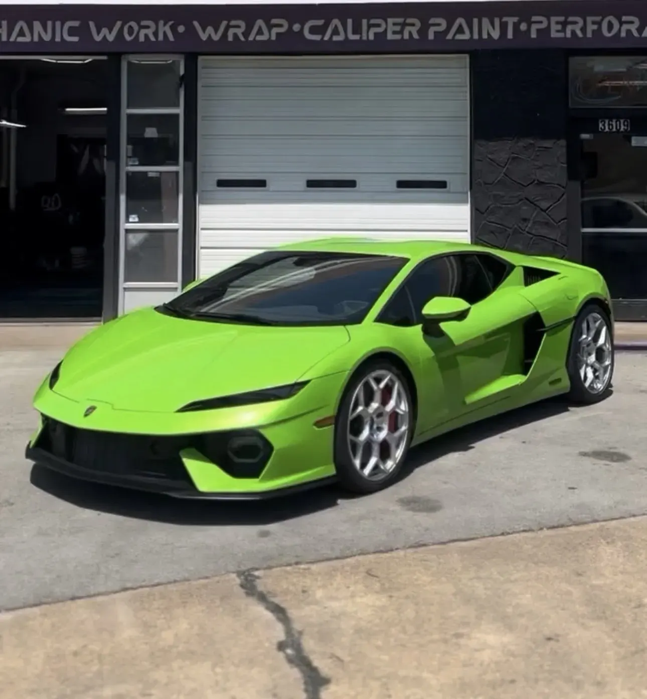 Green Lamborghini with window tint in front of the shop