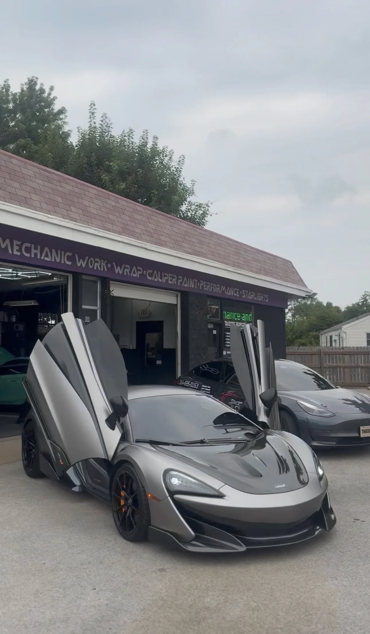 McLaren with its doors up in front of the shop