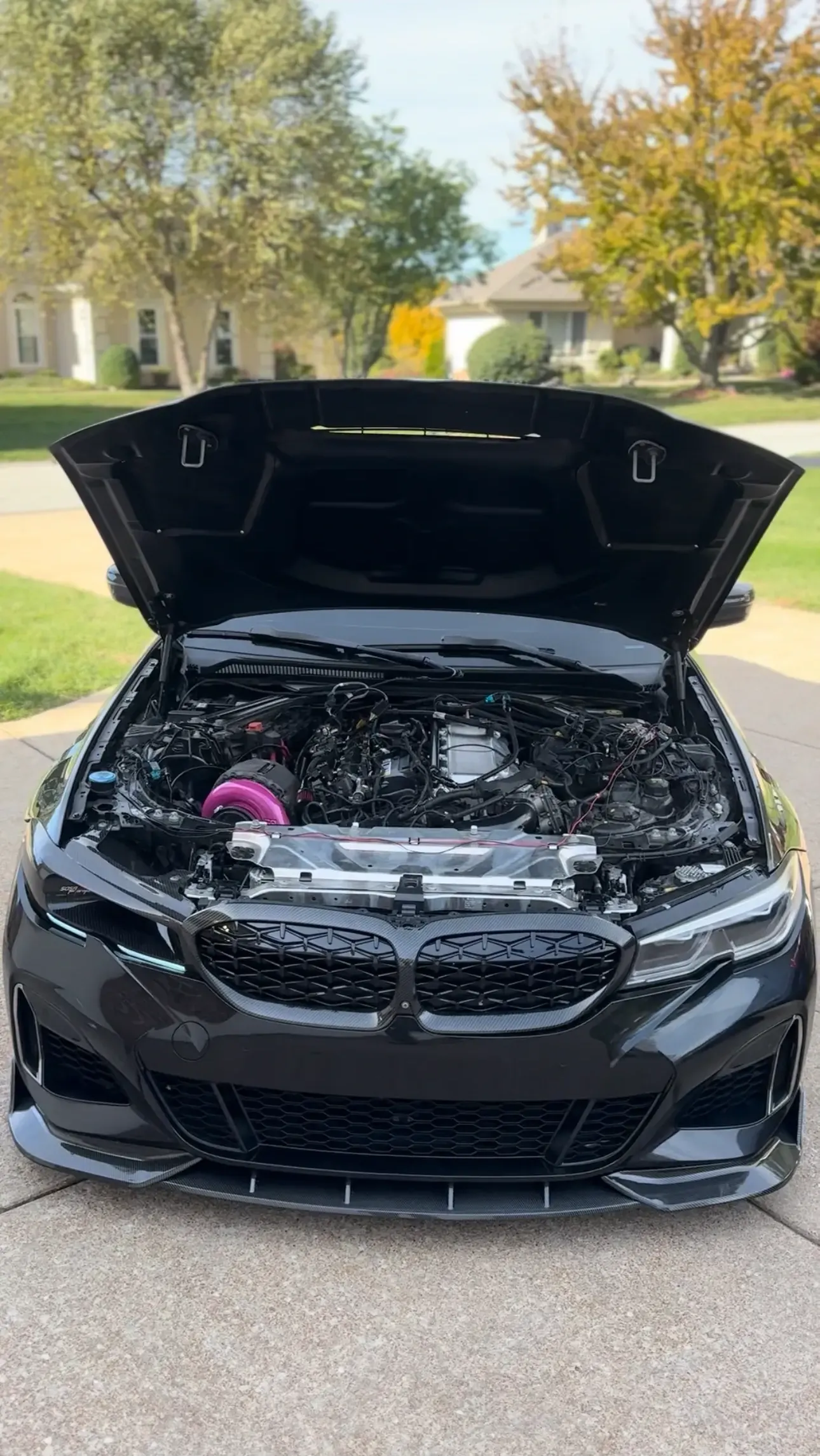 BMW with the hood up and a pink intake